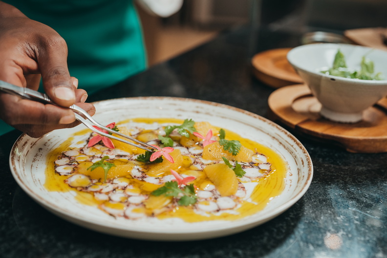 A chef decorating a dish with an edible flower.